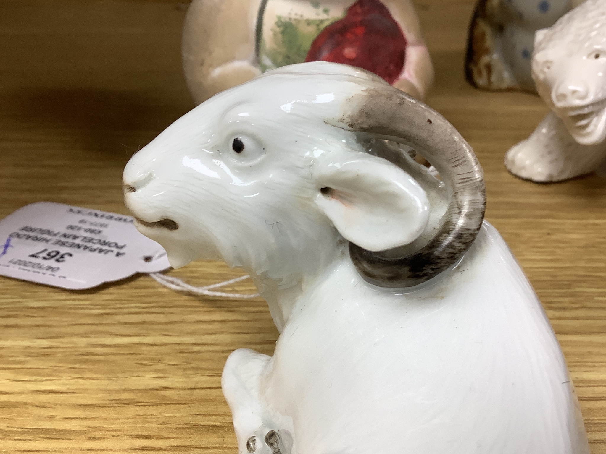 A Japanese Hirado porcelain figure of a polar bear, a Japanese porcelain figure of a ram, two figures of toads and a doll figure